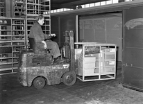 166339 Afbeelding van het beladen van een goederenwagen door Van Gend & Loos met behulp van een heftruck in de ...